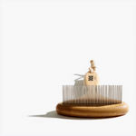 A bamboo dog rake with a round base and long, straight pins, standing upright against a white background.