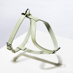 A vegan leather dog harness with silver hardware, featuring a creamy exterior and a pebbled lining in light green.
