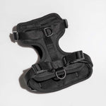 A black dog harness with adjustable straps and carbon coated steel D-rings, designed for comfort and durability.